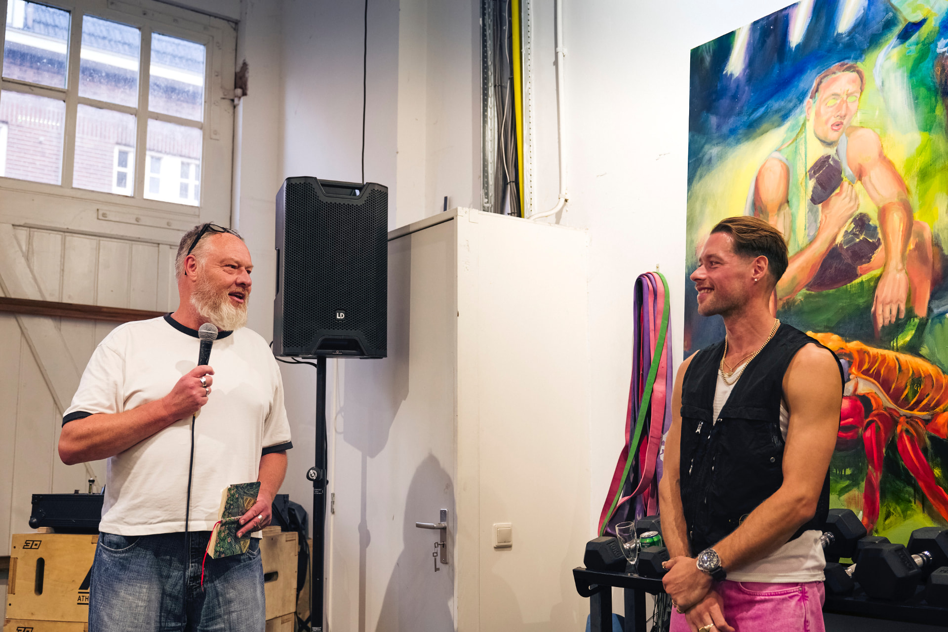 Curator spreekt naast de kunstenaar bij een groot doek