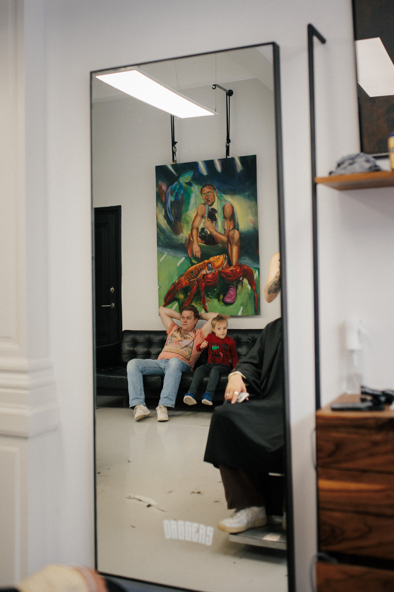 Schilderij en bezoekers weerspiegeld in de barbershopspiegel